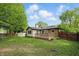 Well-maintained brick home featuring a wooden deck, green lawn, and mature trees in the fenced backyard at 8218 San Carlos Ct, Indianapolis, IN 46256