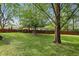 Spacious backyard with lush green grass, mature trees, a wooden fence, and swing set at 8218 San Carlos Ct, Indianapolis, IN 46256