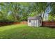 Large backyard featuring a storage shed, wooden fence, green grass, and mature trees at 8218 San Carlos Ct, Indianapolis, IN 46256