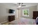 Bright bedroom with ceiling fan, dresser, mounted TV, and a window overlooking greenery at 8218 San Carlos Ct, Indianapolis, IN 46256
