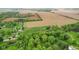 Drone shot revealing the home's position amid rich flora, expansive fields, and community housing, intersected by a road at 8293 Water St, Coatesville, IN 46121