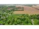 High-angle vista displaying the home's setting, bordered by thick greenery, crop land, and homes, all linked by a road at 8293 Water St, Coatesville, IN 46121