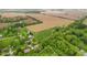 Sweeping aerial shot exhibiting the home's location, framed by dense foliage, arable land, and nearby residences off a road at 8293 Water St, Coatesville, IN 46121