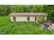 Shows the exterior of the building amid overgrown landscape at 8293 Water St, Coatesville, IN 46121