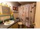 Well-lit bathroom with vanity, decorative mirror, and a floral shower curtain at 8362 Punto Alto Dr, Indianapolis, IN 46227