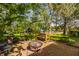 Lush backyard featuring a brick patio with a fire pit, mature trees, and a well-maintained lawn at 8770 N Pennsylvania St, Indianapolis, IN 46240