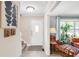 Bright foyer featuring a staircase, white door, and a glimpse into a cozy living room with comfortable seating at 9832 Scotch Pine Ln, Indianapolis, IN 46256