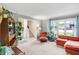 Comfortable living room with neutral carpet, large windows, an orange sofa, and open access to other living spaces at 9832 Scotch Pine Ln, Indianapolis, IN 46256