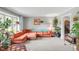 Cozy living room featuring a sectional sofa, large window, and a variety of plants, creating a comfortable and inviting space at 9832 Scotch Pine Ln, Indianapolis, IN 46256