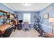 Well-lit home office with a desk, computer, shelving, an elliptical machine, and modern blue walls at 9832 Scotch Pine Ln, Indianapolis, IN 46256