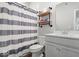 Well-lit bathroom with gray and white striped shower curtain, shelving, and gray cabinets at 10419 Pronghorn Ln, Indianapolis, IN 46239