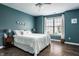 Inviting bedroom with hardwood floors, teal walls, plush bedding, and natural light from a large window at 14805 Chamberlain Dr, Westfield, IN 46074