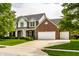 Stunning two-story brick home featuring a three-car garage, manicured lawn and mature trees at 14805 Chamberlain Dr, Westfield, IN 46074