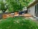 View of a backyard featuring a wooden deck, sliding glass door, grill, and green grass at 1612 Prairieview Ln, Greenfield, IN 46140