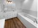 All white primary bath features a soaking tub, dual sinks and hardwood floors at 1726 Creekside W Ln, Carmel, IN 46032
