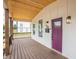 Close-up of a covered front porch featuring wooden floors and a stylish purple front door at 1825 E Maryland St, Indianapolis, IN 46201