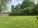 The large backyard boasts a lush lawn bordered by a wooden fence and mature trees, creating a serene outdoor space at 1927 E 125 S, Franklin, IN 46131