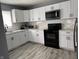 Bright kitchen featuring white cabinets, gray backsplash, and stainless steel appliances at 322 S Rural St, Indianapolis, IN 46201