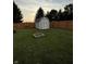 Backyard shed with a fire pit area surrounded by a wooden fence and lush green lawn at 3292 Underwood Dr, Whiteland, IN 46184