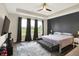 Relaxing main bedroom with a tray ceiling, dark accent wall, ceiling fan, and natural light from the windows at 3592 Gillsland Rd, Bargersville, IN 46106