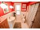 Red bathroom with a pedestal sink, plaid shower curtain, and white-tiled walls at 4163 Otterbein Ave, Indianapolis, IN 46227