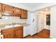 Kitchen features wood cabinets, white appliances, and view to a closet and exterior exit at 4504 Harvard Dr, Anderson, IN 46013