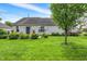 Spacious backyard featuring green grass, mature tree, patio and sliding glass doors at 482 Sycamore St, Brownsburg, IN 46112
