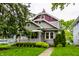 Charming home featuring grey siding, lush lawn, mature trees, and a covered front porch at 5015 N Park Ave, Indianapolis, IN 46205