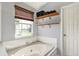 Relaxing bathroom showcasing a large soaking tub, natural light from the window, and shelving for storage at 5041 Millwright Ct, Indianapolis, IN 46254