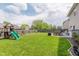 Large backyard features a playset, a fire pit, patio seating, and green grass at 5913 Monticello Square Ln, Indianapolis, IN 46234
