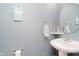 Cozy half bathroom featuring a pedestal sink, round mirror and light blue walls with beach-themed decor at 5913 Monticello Square Ln, Indianapolis, IN 46234