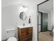 Bathroom featuring a sleek vanity with modern fixtures, a round mirror, and an adjacent toilet for convenience at 6102 Primrose Ave, Indianapolis, IN 46220