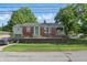 Charming brick home with a green door, garage, retaining wall, and well-manicured front yard at 6102 Primrose Ave, Indianapolis, IN 46220