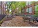 A cozy courtyard with bench seating offers a tranquil outdoor space amidst mature trees at 630 N College Ave # 105, Indianapolis, IN 46204