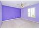 A bedroom with bright purple walls, neutral carpet, a white ceiling fan, and a window with white shutters at 6406 Longhorn Ct, Indianapolis, IN 46237