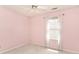 A cozy bedroom with soft pink walls, neutral carpet, a window with delicate lace curtains and a ceiling fan at 6406 Longhorn Ct, Indianapolis, IN 46237