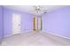 A main bedroom painted purple with neutral carpet, a white ceiling fan, and doorways to a closet and en suite at 6406 Longhorn Ct, Indianapolis, IN 46237