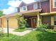 Two-story townhouse with tan garage door, lush lawn, and charming front porch detail, offering classic curb appeal at 6723 Silver Tree Dr, Indianapolis, IN 46236