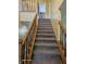 Carpeted staircase with wood railings leading to a hallway with doors and access to the upper level at 6723 Silver Tree Dr, Indianapolis, IN 46236