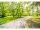 A serene scene of a long gravel driveway winding through lush, green trees at 6762 S State Road 67, Pendleton, IN 46064