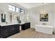Bright bathroom features dual vanity with black cabinetry, quartz countertop, freestanding tub, and pendant lighting at 7116 Trail Ridge Ln, Indianapolis, IN 46259