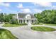 Beautiful home featuring a circular driveway, lush lawn, mature trees, and a classic pillared porch at 7182 Hunt Club Dr, Zionsville, IN 46077