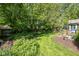 Private backyard with a manicured lawn, mature trees, and garden beds at 8330 Claridge Rd, Indianapolis, IN 46260