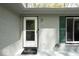 Close up of a well-lit entryway with a 'welcome' mat, green shutters, and a white painted brick exterior at 8581 N Goat Hollow Rd, Mooresville, IN 46158