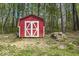 A charming red storage shed with white trim is tucked away in a wooded area at 8581 N Goat Hollow Rd, Mooresville, IN 46158