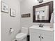 Clean bathroom with white vanity, toilet, and framed mirror and a funny sign at 8635 Nolan Dr, Fishers, IN 46038