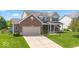 Traditional brick home with a two-car garage, well-manicured lawn, and a welcoming front porch at 8635 Nolan Dr, Fishers, IN 46038
