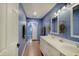 Bathroom featuring double vanity with white cabinets, framed mirrors, blue walls, and wood-look flooring at 1009 Broadway St, Indianapolis, IN 46202