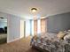 Well-lit bedroom with a queen bed, window with curtains, and light blue painted walls at 10836 Zimmerman Ln, Indianapolis, IN 46231