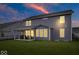 Spacious backyard with a covered patio, green lawn, and a two-story home under a colorful sunset at 10993 Liberation Trce, Noblesville, IN 46060